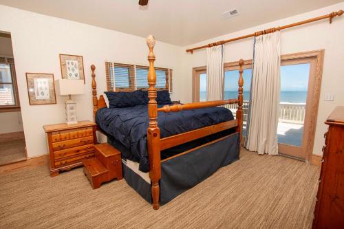 a bedroom with a bed and a balcony with the ocean at PI76, Life of Reilly- Oceanfront, Ocean Views, Private Pool, Private Beach Access, Foosball in Corolla