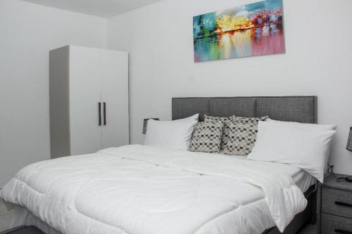 a white bedroom with a bed with white sheets and pillows at A307 Luxury 1 Bedroom in Accra