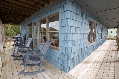 a blue house with rocking chairs on a deck at Soundfront, Sound Views, Kayak! PT1402, Keene ll in Sanderling