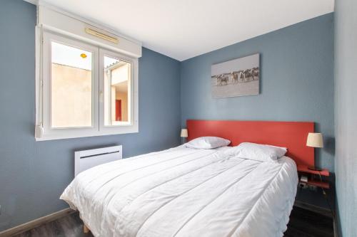 una camera con letto con testiera rossa e finestra di Le Mayflower a Le Grau-du-Roi