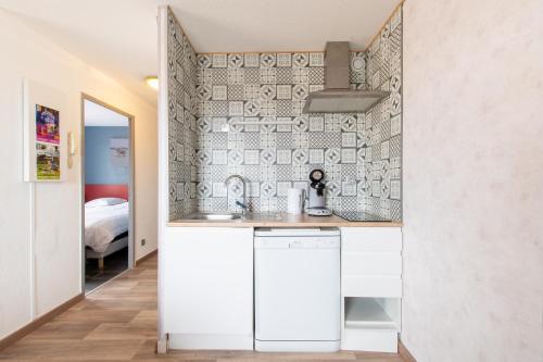 una piccola cucina con mobili bianchi e una parete di Le Mayflower a Le Grau-du-Roi