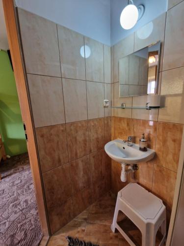 a bathroom with a sink and a mirror and a stool at Pokoje Gościnne u Lańdy in Poronin