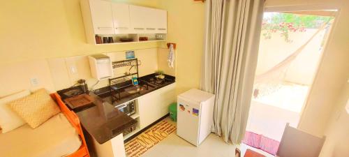 a small kitchen with a small refrigerator and a window at Chalé com ar condicionado e garagem in Alto Paraíso de Goiás