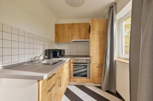 a kitchen with wooden cabinets and a sink and a window at NEW-Emma - Glashofen Walldürn in Walldürn