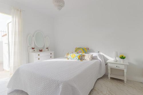 1 dormitorio blanco con 1 cama blanca y 2 espejos en Bungalow con encanto, en San Juan de Alicante