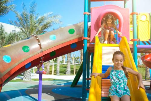 a little girl playing on a slide at a playground at The Art Hotel & Resort in Manama