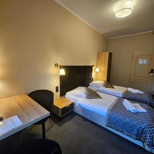 a hotel room with two beds and a desk and a table at Willa Kłodzko-Zacisze - sauna, siłownia, komnata solna, parking in Kłodzko