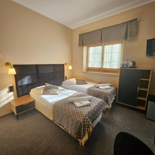 a hotel room with two beds and a television at Willa Kłodzko-Zacisze - sauna, siłownia, komnata solna, parking in Kłodzko