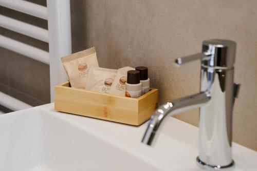 uma caixa de produtos sentados num balcão ao lado de um lavatório em LaMì Room & Apartment em Castel San Pietro Terme
