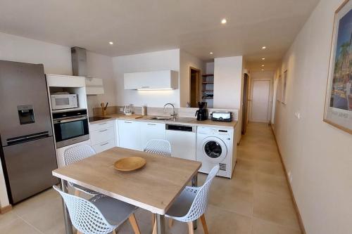 une cuisine avec une table, des chaises et un évier dans l'établissement Front de mer - Emplacement prisé au calme - T2 moderne et entièrement climatisé - Tout à pieds, à Sanary-sur-Mer