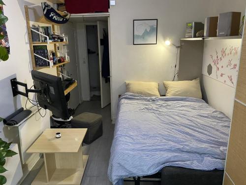 une petite chambre avec un lit et une télévision dans l'établissement Studio confortable Paris, à Paris