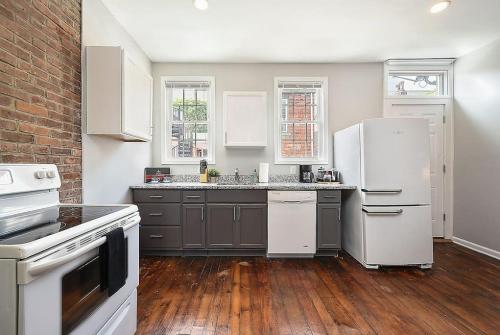 a kitchen with white appliances and a brick wall at HostWise Stays - The "Row" House - Beautiful Space, Two King Beds in Pittsburgh