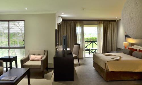 Habitación de hotel con cama y sala de estar. en Cresta Riley's Hotel en Maun