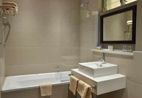 a bathroom with a sink and a bath tub at Cresta Riley's Hotel in Maun