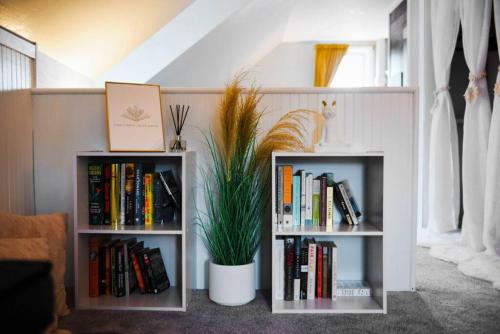 two book shelves filled with books and a potted plant at HostWise Stays - The Geneva - Easy Walk to Childrens in Pittsburgh