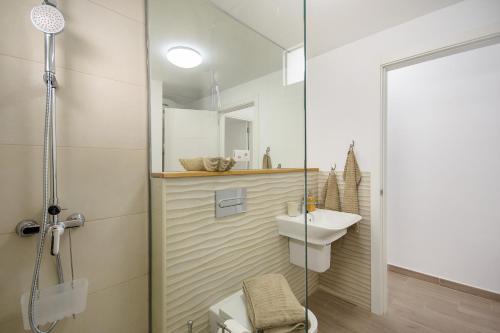 une salle de bains avec douche, toilettes et lavabo dans l'établissement Blue Volcano-pool, gym and activities in Sport Center Fariones included, à Puerto del Carmen