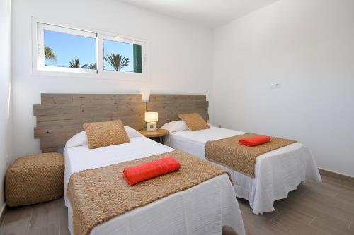 2 łóżka z pomarańczowymi poduszkami w pokoju w obiekcie Blue Volcano-pool, gym and activities in Sport Center Fariones included w Puerto del Carmen
