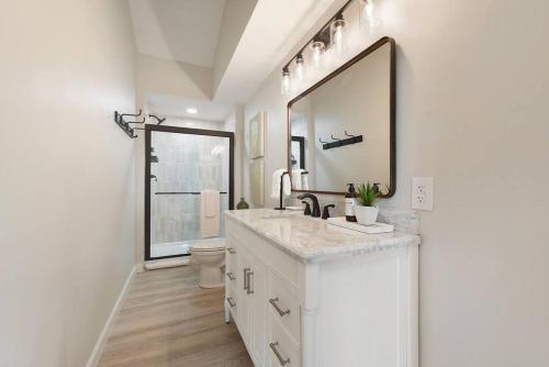 a white bathroom with a sink and a mirror at The Cielo - Ohio River Views in the City in Pittsburgh