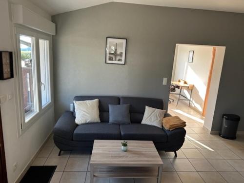 a living room with a blue couch and a table at Le Nid Du Moulin in Batzendorf
