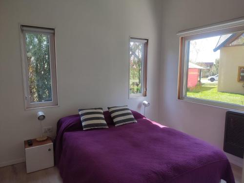 um quarto com uma cama roxa e 2 janelas em Casa nueva en Bariloche a orillas del Nahuel Huapi em San Carlos de Bariloche