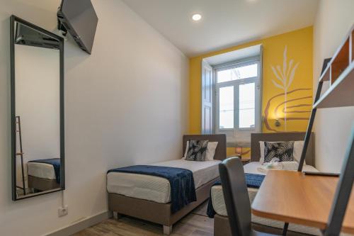 a small room with a bed and a mirror at Leevin Guesthouse in Faro