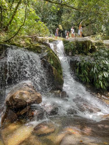 people are standing on a waterfall in a forest at Taibará Refugio Natural in San Carlos