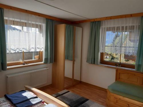 a bedroom with two windows with green curtains and a bed at Ferienwohnung Haus Bergfrieden in Gerlosberg