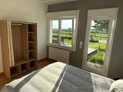 1 Schlafzimmer mit einem Bett und 2 Fenstern mit Aussicht in der Unterkunft Le Nid Du Moulin in Batzendorf