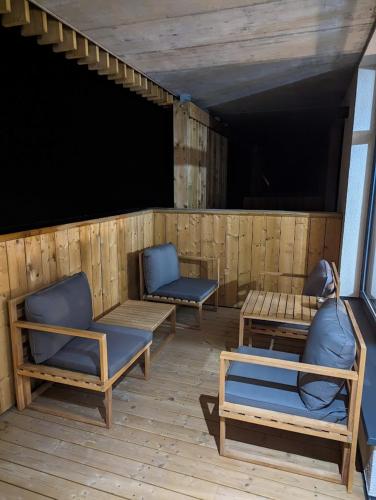 two blue chairs and tables on a wooden patio at Zadov - Apartmán Srdce Šumavy in Stachy