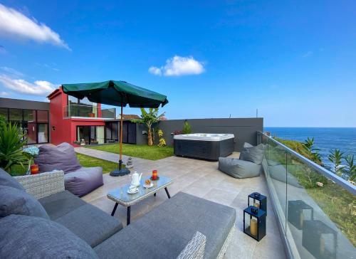 a patio with a couch and an umbrella at Terra Vivaz - Porto Bay Villa in Porto Formoso