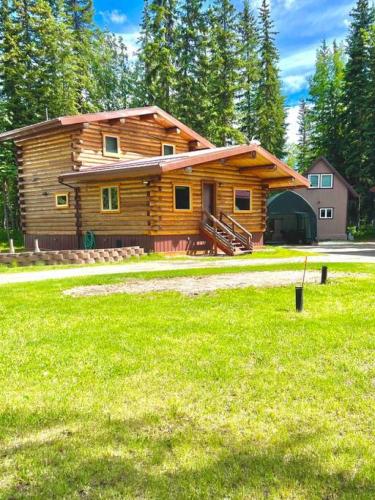 a log cabin with a grass field in front of it at The Alaskan Dream Lodge in Fairbanks