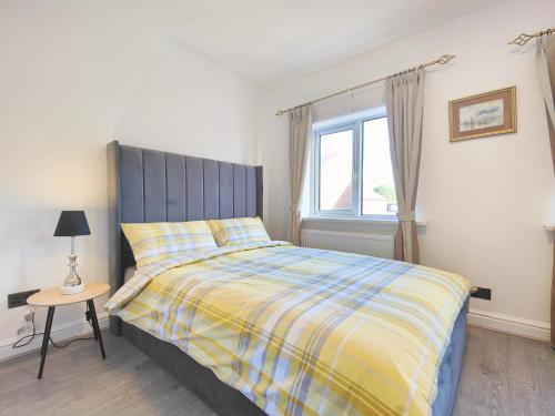 a bedroom with a bed with a blue headboard and a table at Regent House - Modern Holiday Home 10 Minutes to Manchester City Centre With Free Parking in Manchester