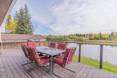 a table and chairs on a deck with a view of a lake at The Chena River House South Suite in Fairbanks