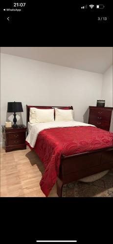 a bedroom with a bed with a red blanket and two night stands at Cozy greenery view among comfort in Haledon