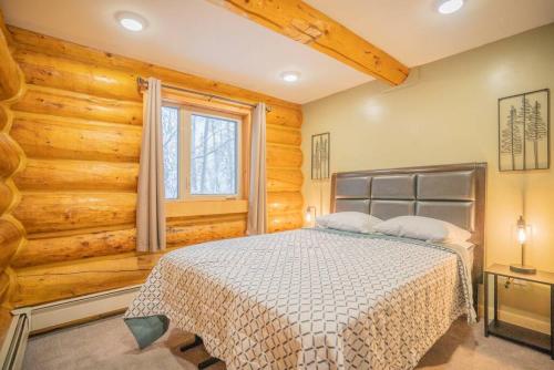 a bedroom with a bed in a room with wooden walls at Tucked Away Timber Lower Suite in Fairbanks