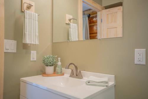 ein weißes Badezimmer mit einem Waschbecken und einem Spiegel in der Unterkunft Tucked Away Timber Lower Suite in Fairbanks