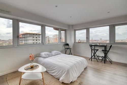 a white bedroom with windows and a bed and a table at BD MINIMES - Parking Free - Proche gare - Vue in Toulouse