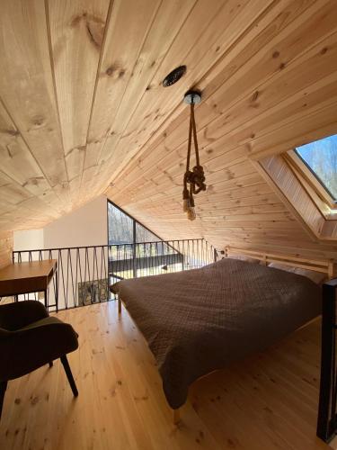 a bed in a room with a wooden ceiling at Mała Holenderka - Lewy Brzeg Narwi in Burlaki