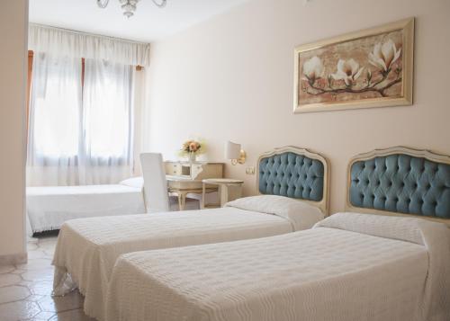 a hotel room with two beds and a table at Hotel Villa Serena in Marghera