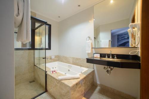 a bathroom with a bath tub and a sink at Faro Hotel Taubaté in Taubaté