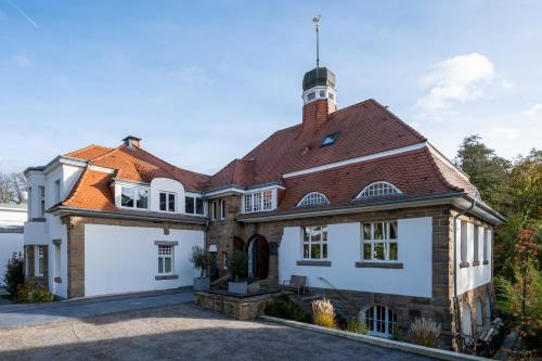 una gran casa blanca con techo rojo en DESIGN-Studio CHURCH 46 en Mülheim an der Ruhr