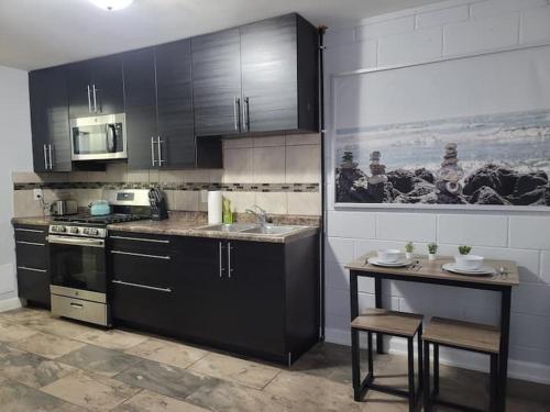 a kitchen with black cabinets and a sink and a table at Nice and cozy apartment in Ypsilanti