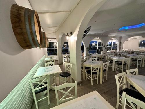 a restaurant with white tables and chairs and a barrel at Castro Hotel in Amoudara Herakliou