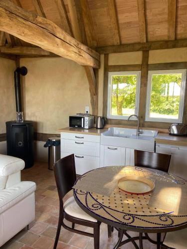 une cuisine avec une table, des chaises et un évier dans l'établissement Gîtes Normands de charme les châtaigniers, à Bretteville-du-Grand Caux