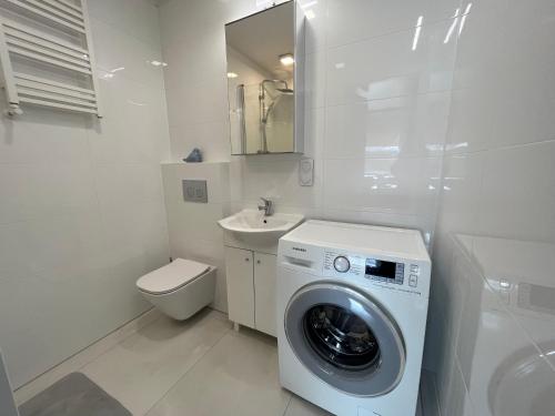 biała łazienka z pralką i umywalką w obiekcie Apartament Słoneczne Szczecin w Szczecinie