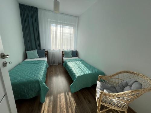 Pokój z 2 łóżkami, krzesłem i oknem w obiekcie Apartament Słoneczne Szczecin w Szczecinie