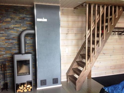 a wood stove in a room with a staircase at Inarin Kalakenttä in Inari