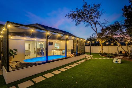 a glass house with a swimming pool at night at Cozy Clearwater Getaway Beach, Spa, and Luxury in Clearwater