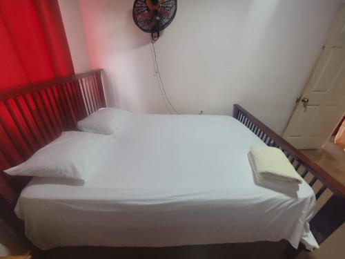 Un dormitorio con una cama blanca con un libro. en Alojamientos Hermanos Zambranos, en Cabra