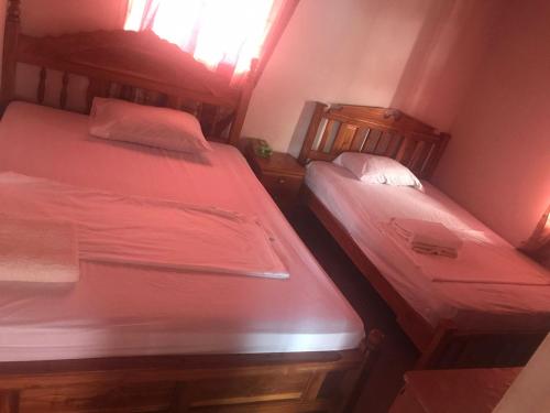 2 camas en una habitación pequeña con sábanas rojas en Alojamientos Hermanos Zambranos, en Cabra
